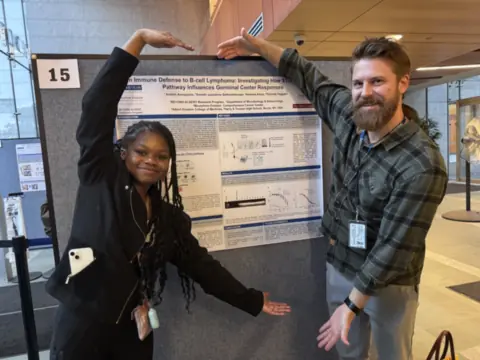 Andrea Amegashie and Thomas Hägglöf beside Andrea's poster at the 2026 BEYOND ALBERT Symposium